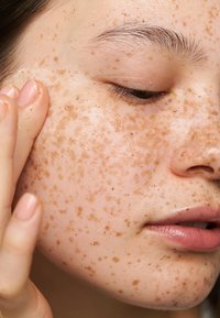 Exfolierande skrubb appliceras på huden, med en lätt konsistens som har korniga bruna prickar och en jämn, något glansig yta.