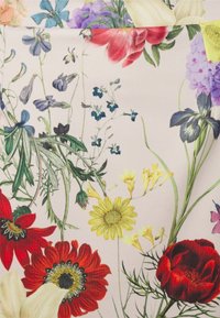 Květinová tkanina s živými červenými, žlutými a modrými květinami na světle růžovém pozadí, s podrobnou texturou a různými tvary.