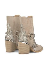 Stivali da cowboy in suede beige con un motivo a pelle di serpente testurizzato sui lati, abbelliti da accenti di strass e un tacco impilato.