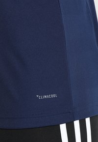 Mörkblå Climalcool träningsskjorta med texturerad tyg, kontrasterande sidopaneler och en vit logo längst ner.