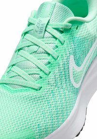 Chaussette de sport vert menthe avec un dessus en maille texturée, des lacets clairs et un swoosh Nike blanc. Semelle rembourrée avec des accents de bande noire.