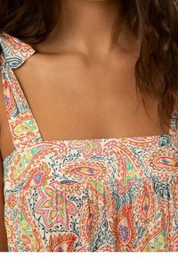 Robe à motifs floraux en tissu doux. Présente des bretelles larges et un buste froncé, avec des motifs paisley et de feuilles colorés sur un fond clair.