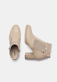 Stivali alla caviglia beige con tomaia in pelle liscia, pannelli in rete e tacco a blocco. Decorati con una zip laterale e dettagli con strap decorativi.