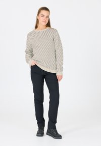 Hellgrauer Pullover mit schwarzen Punkten, Rundhalsausschnitt, gerippte Bündchen, kombiniert mit schwarzen Hosen und schwarzen Schnürstiefeln auf weißem Hintergrund.
