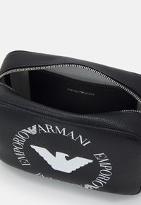 Black leather pouch with a textured finish, featuring a silver zipper and white Emporio Armani logo with an eagle design. Interior is lined.