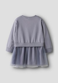 Grå kjole med lange ermer, med en ensfarget overdel og et lagvis, gjennomsiktig tyllskjørt. Har rund hals og ribbestrikkede mansjetter.