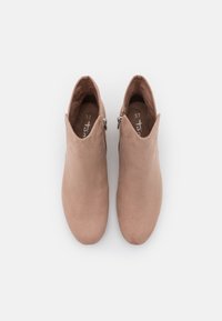 Rosa Wildleder-Stiefeletten mit spitzem Zeh und geschwungener Kragenlinie. Seitlicher Reißverschluss und durchgehend glatte Textur.