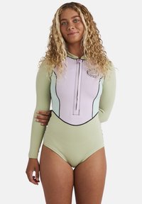 Mutino a maniche lunghe in verde chiaro e viola pastello, con zip frontale, cuciture nere e un logo circolare sul petto.