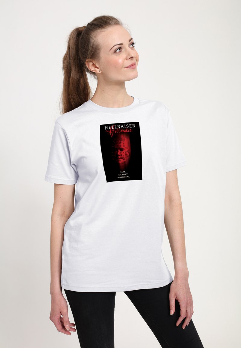 Bílý bavlněný tričko s tmavým grafickým potiskem a červenými akcenty, zobrazující text "Hellraiser" a design s hororovou tématikou.