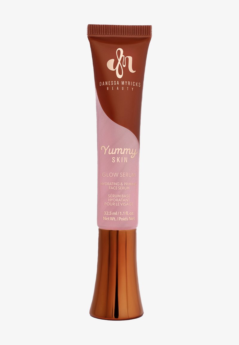 En brun och rosa tub av Yummy Skin Glow Serum med en glänsande yta, som har guldtext och en utformad bas. Volym: 32,5 ml.