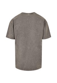 Tricou gri cu mânecă scurtă, cu un croi lejer, realizat dintr-un material moale. Are un decolteu rotund și o textură ușor decolorată pentru un aspect vintage.