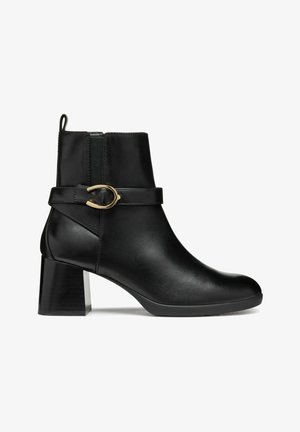 Svart ankelboots i slät läder med rund tå, sidodragkedja och en dekorativ rem med ett spänne i guldton. Kraftig klack.