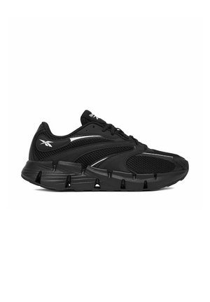 Czarny sportowy sneaker z cholewką z siateczki, rzeźbioną podeszwą z głębokimi rowkami oraz białym logo Reebok na pięcie i języku.