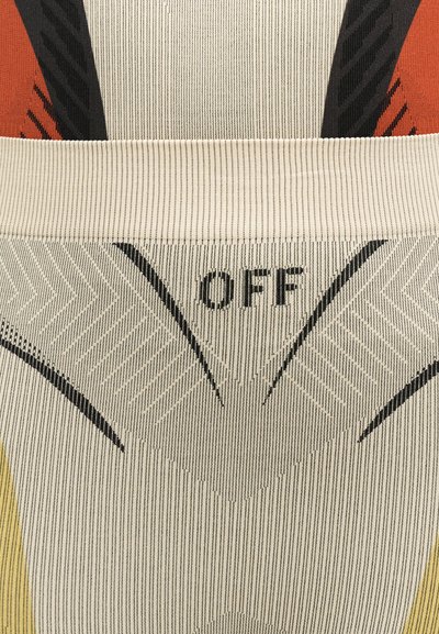 Κοντινή λήψη υφάσματος με υφαντό σχέδιο που περιλαμβάνει τη λέξη "OFF" και γεωμετρικά σχήματα σε μαύρο, κρεμ, κόκκινο και κίτρινο χρώμα.