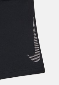 Czarne spodenki sportowe z ukośnym białym logo Nike w postaci smugi, ozdobione paskami. Gładki materiał i dopasowany krój.
