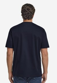 Mörkblå bomullströja med rund hals och korta ärmar, med en avslappnad passform och utan synliga logotyper eller mönster.