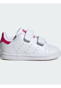White sneakers with pink accents, made of synthetic material. Features two Velcro straps, perforated detailing on the sides, and a textured sole.