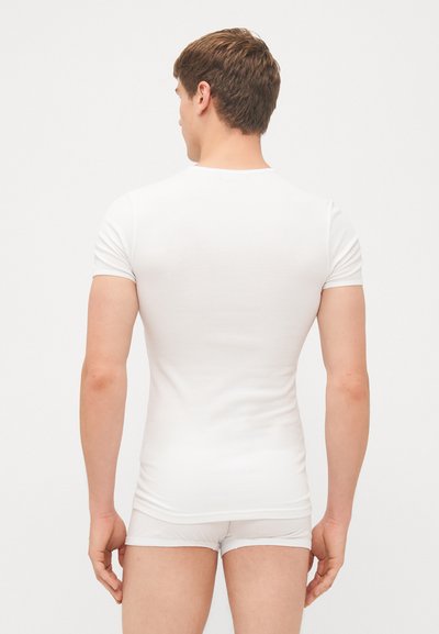 T-shirt bianco aderente a maniche corte con scollo tondo. Tessuto morbido e liscio. Design minimalista, senza loghi o motivi visibili.