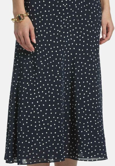 Marineblauer Rock mit weißen Tupfen und fließendem Design, gefertigt aus leichtem Stoff, mit einem Saum, der sich frei bewegt.