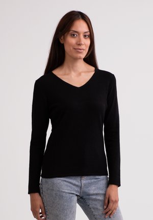 Zwarte gebreide trui met lange mouwen en een V-hals ontwerp. Zachte textuur, fitted silhouet en een gladde afwerking. G gedragen met lichtgewassen jeans.