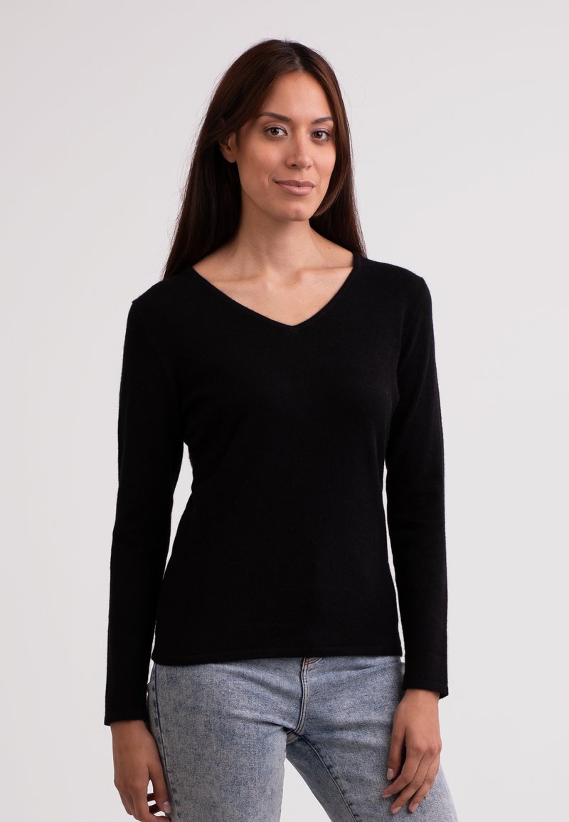 Sort strikweave sweater med lange ærmer og V-hals design. Blød tekstur, tætsiddende silhuet og en glat overflade. Bæres med lyse vaskede jeans.