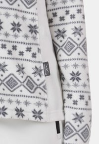 Witte fleecetrui met grijze sneeuwvlok- en geometrische patronen. Voorzien van een ritszak en een label met de merknaam.