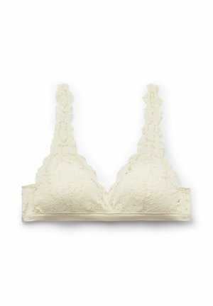 Kremowy koronkowy biustonosz typu bralette z kwiatowymi wzorami, falistymi krawędziami i regulowanymi koronkowymi ramiączkami, rozłożony na płasko na białym tle.
