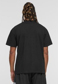 Sort kortærmet t-shirt med en afslappet pasform, lavet af blødt bomuldsstof, har en glat tekstur og et enkelt, udekoreret design.