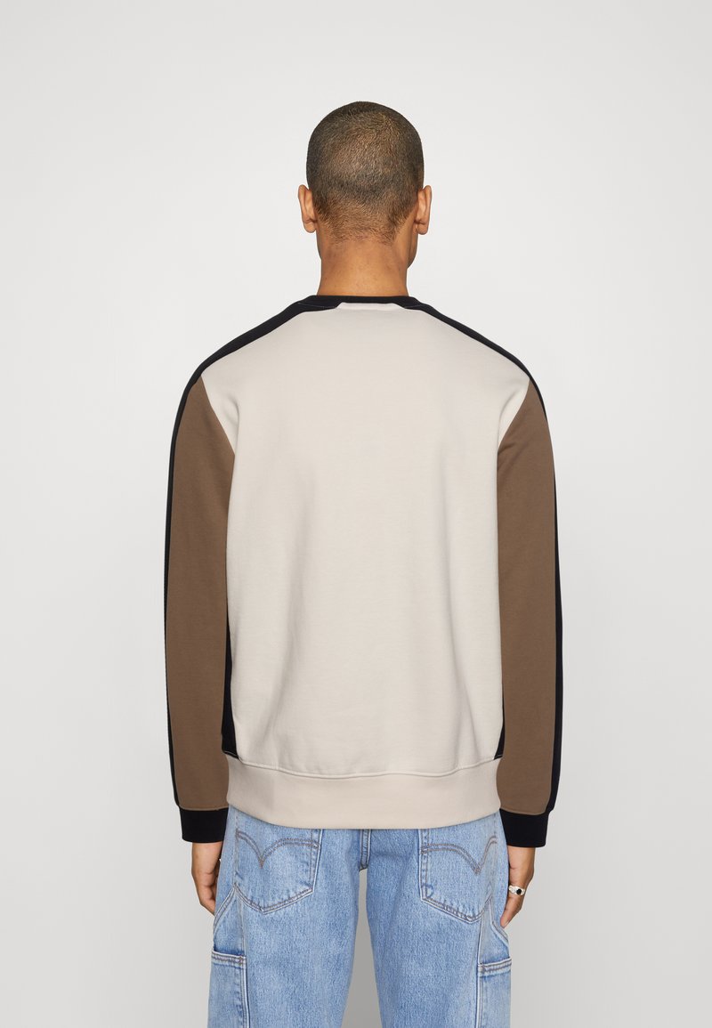Felpa girocollo con un corpo beige e accenti marroni, neri e blu sulle maniche, realizzata in morbido cotone.
