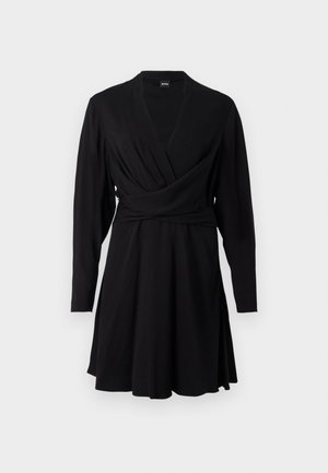 Rochie neagră, dintr-un material moale, având mâneci lungi, un decolteu în formă de V și o fustă evazată, concepută pentru a evidenția o siluetă ajustată.