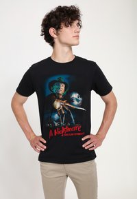 Schwarzes Baumwoll-T-Shirt mit einem Grafikdesign von Freddy Krueger und dem Gesicht einer Frau, ergänzt durch fetten roten Text mit der Aufschrift "A Nightmare on Elm Street."