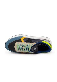 Zapatilla con una mezcla de malla gris, ante azul, acentos amarillos y negros. Presenta cordones texturizados, una suela acolchada y un logo en la lengüeta.