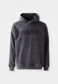 Juodas džemperis su priekine kengūros kišene, siuvinėtu "adidas" logotipu, raštuotomis rankovėmis ir tekstūruotu audiniu. Yra su raištelių kapišonu.