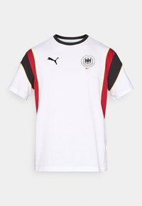 Άσπρο κοντομάνικο μπλουζάκι με μαύρες, κόκκινες και κίτρινες λεπτομέρειες. Περιλαμβάνει το λογότυπο Puma και το εθνόσημο της Γερμανίας στο στήθος.