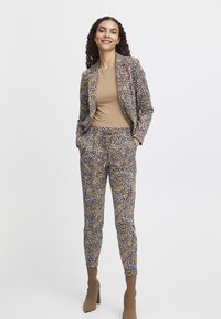 Blazer- und Hosen-Set im mehrfarbigen Punkte-Muster mit braunen, blauen und cremigen Akzenten. Glattes Material, schmaler Schnitt und taillierte Beinform.