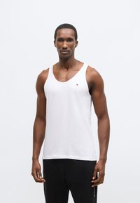 Maiou alb fără mâneci din bumbac, cu un accent subtil de logo pe piept și un croi relaxat, dar ajustat.