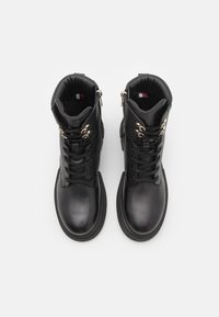Bottines en cuir noir avec un bout arrondi, un laçage à l'avant et des accents en métal doré. Elles comportent une fermeture éclair et un col rembourré.