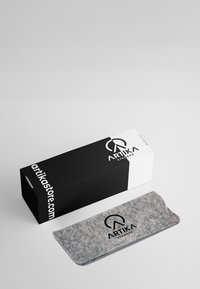 Custodia per occhiali grigia accanto a una scatola bianca e nera etichettata "ARTIKA Eyewear", con logo e testo del sito web. Texture liscia, forma rettangolare.