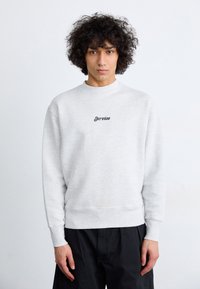 Light gray sweatshirt with a crew neckline and ribbed cuffs. Features black embroidered text "Service" on the chest. Smooth cotton blend fabric.