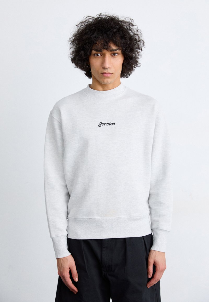 Light gray sweatshirt with a crew neckline and ribbed cuffs. Features black embroidered text "Service" on the chest. Smooth cotton blend fabric.