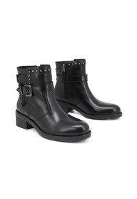 Stivaletti in pelle nera, con punta tonda, borchie argentate sulla caviglia, zip laterale e tacco spesso. Presentano una cintura decorativa.