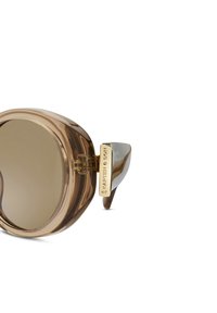 Gafas de sol marrones de gran tamaño con montura transparente, lentes oscuros y detalles dorados en las patillas; presentan una forma geométrica definida.