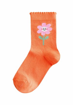 Orange sok med ribbet kant, der har et pink blomstermotiv med et smilende ansigt og grøn stilk. Glat tekstur, standard ankellængde.