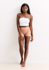 Beige naadloze shorts en een witte strapless crop top. De shorts hebben een gladde textuur en zitten net boven de middelste dij, met eenvoudige ontwerpelementen.