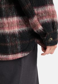 Vezelige zwart en roze geruite jas met knoopmanchetten, die een textuur van een wolmix en een afgeronde zoom laat zien, met zachte, gelaagde vezels.