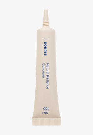 El corrector de luminosidad natural de Korres en un tubo delgado, de color crema con texto azul, coronado por una punta de aplicador estrecha para una aplicación precisa.