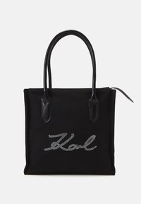 Black canvas tote bag with leather handles, featuring a silver rhinestone 'Karl' logo on the front. Simple rectangular design.