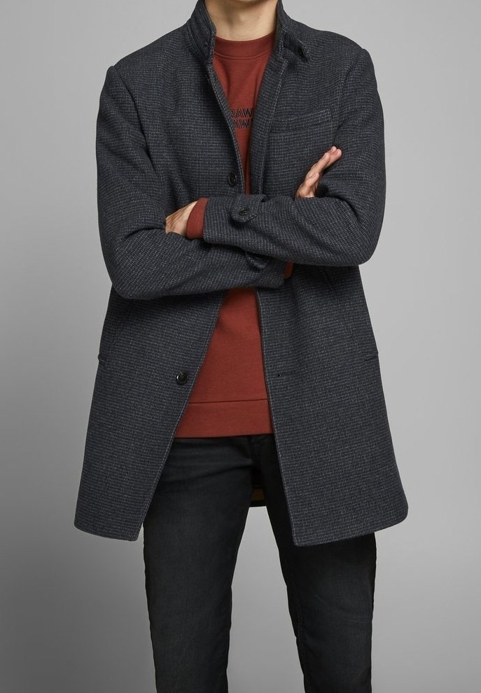 Mörkgrå ylleblandad kappa med ett strukturerat mönster, med ståkrage, framknappar och sidofickor, som bärs över en röd sweatshirt.