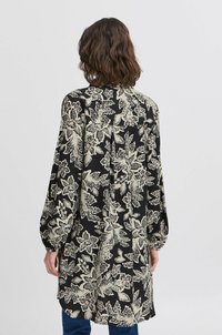 Abito nero a maniche corte con motivo floreale beige, caratterizzato da una linea dritta, chiusura a bottoni sul retro e maniche leggermente a sbuffo.