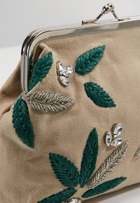 Beige stof clutch med metalramme, dekoreret med grønne broderede blade, sølvperleblade og klare stenklaser.